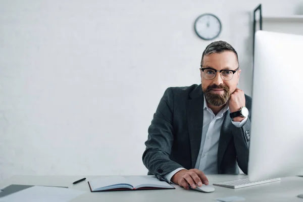 Guapo hombre de negocios en ropa formal y gafas mirando a la cámara - foto de stock