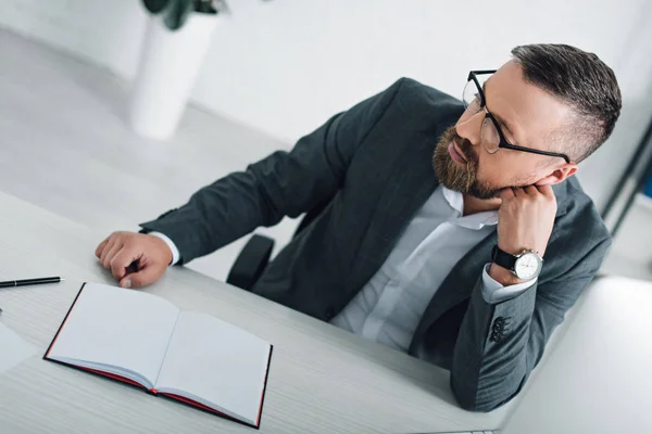 Schöner Geschäftsmann in formeller Kleidung und Brille, der im Büro wegschaut — Stockfoto