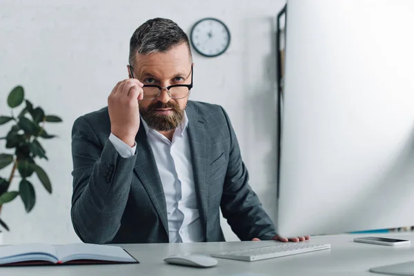 Handsome businessman in formal wear and glasses looking at camera in office — Stock Photo