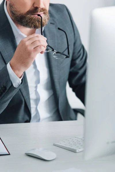 Cropped view of businessman in formal wear holding glasses in office — Stock Photo