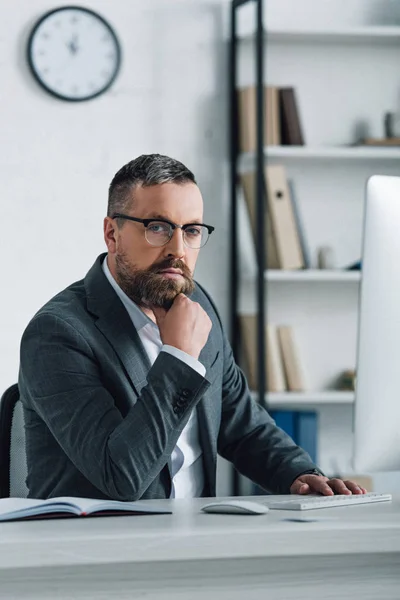 Schöner Geschäftsmann in formeller Kleidung und Brille, der im Büro in die Kamera schaut — Stockfoto