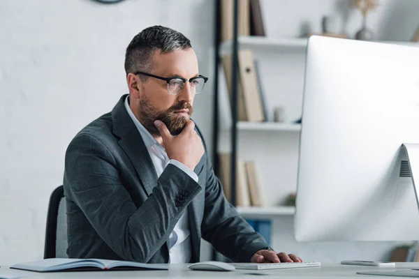 Schöner Geschäftsmann in formeller Kleidung und Brille, der auf den Computer schaut — Stockfoto