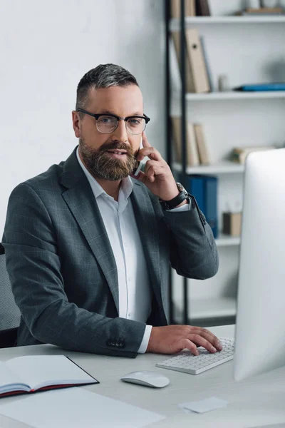 Bel homme d'affaires en tenue formelle parlant sur smartphone et regardant la caméra — Photo de stock