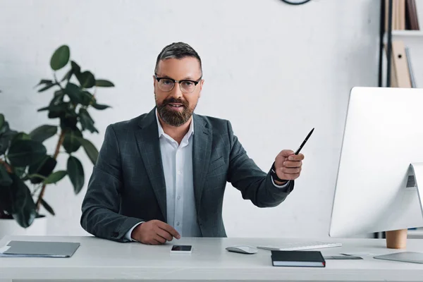 Guapo hombre de negocios en formal desgaste celebración de la pluma y mirando a la cámara - foto de stock