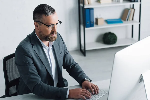 Bel homme d'affaires en tenue formelle et lunettes à l'aide d'un ordinateur — Photo de stock