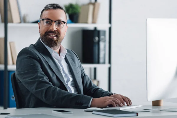 Hombre de negocios guapo en ropa formal y gafas usando la computadora - foto de stock
