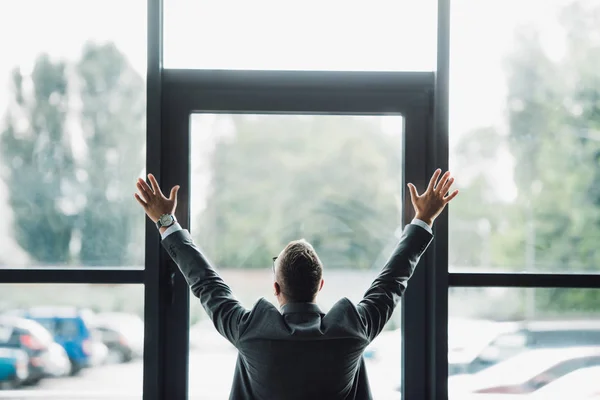 Vista trasera del hombre en desgaste formal con las manos extendidas - foto de stock