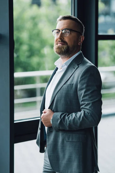 Homem de negócios bonito no desgaste formal e óculos olhando para longe — Fotografia de Stock