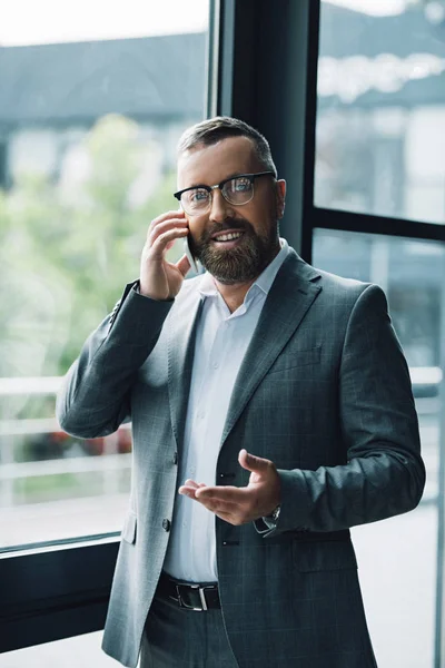 Handsome businessman in formal wear and glasses talking on smartphone — Stock Photo