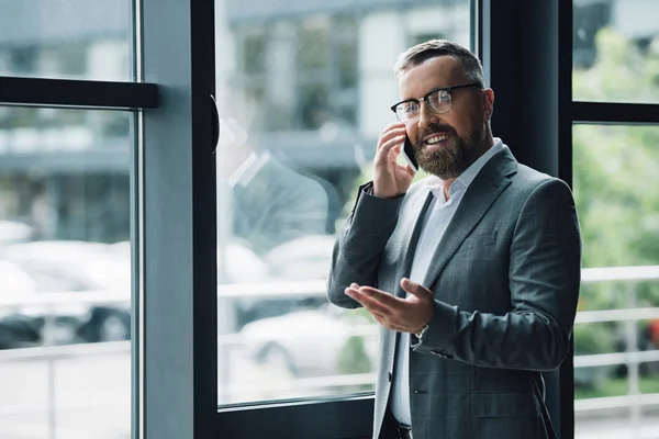 Hombre de negocios guapo en ropa formal y gafas hablando en el teléfono inteligente - foto de stock