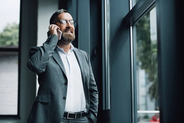 Homem de negócios bonito no desgaste formal e óculos falando no smartphone — Fotografia de Stock