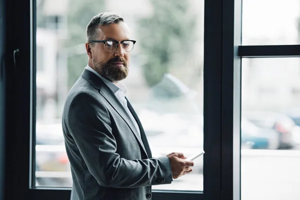 Guapo hombre de negocios en ropa formal y gafas con teléfono inteligente - foto de stock