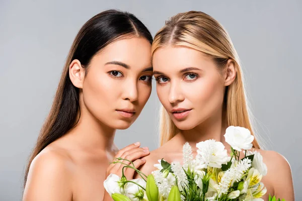 Schöne blonde und asiatische Brünette nackte Mädchen mit Blumen isoliert auf grau — Stockfoto