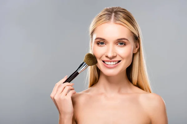 Souriant jeune femme nue avec pinceau cosmétique isolé sur gris — Photo de stock