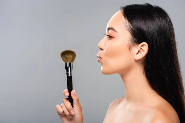 Side view of beautiful naked asian woman with cosmetic brush isolated on grey — Stock Photo