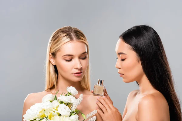 Schöne nackte Frauen mit Blumen und Parfüm isoliert auf grau — Stockfoto