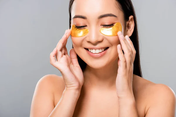 Smiling naked asian woman with eye patches on face isolated on grey — Stock Photo