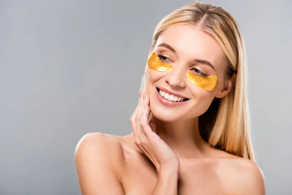 Happy naked blonde young woman with eye patches looking away isolated on grey — Stock Photo