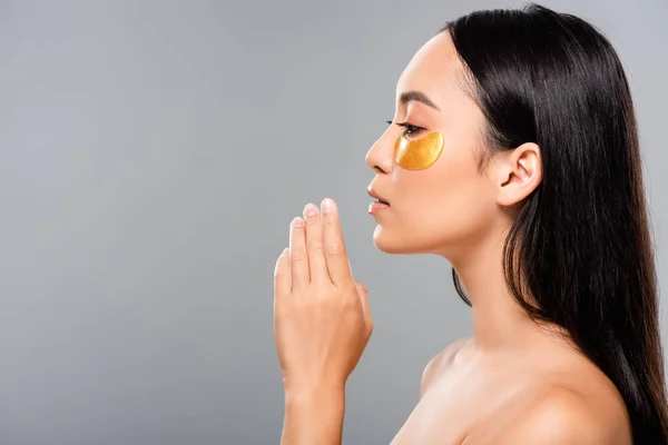 Side view of brunette naked asian woman with eye patches on face isolated on grey — Stock Photo