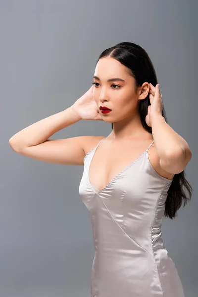 Attractive asian woman in satin dress with red lips isolated on grey — Stock Photo
