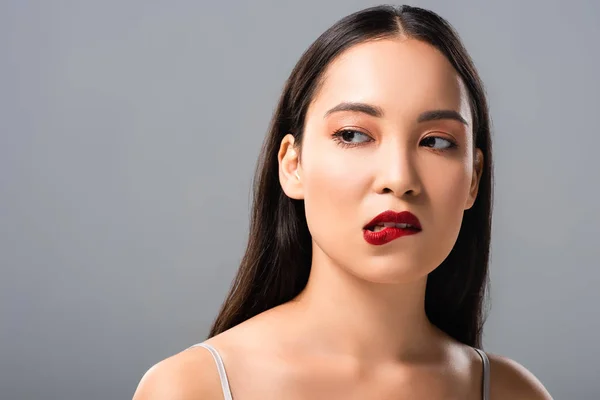 Красива азіатська жінка кусає червоні губи ізольовані на сірому — стокове фото