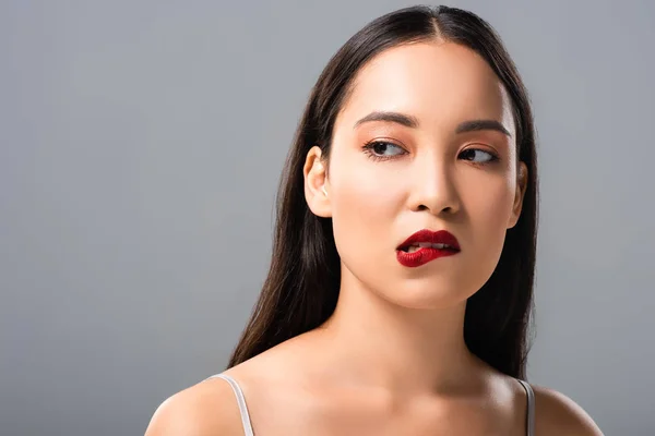 Beautiful asian woman biting red lips isolated on grey — Stock Photo