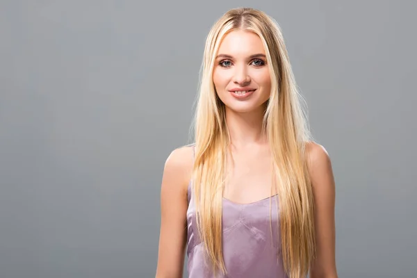 Souriant élégante fille blonde en robe de satin violet isolé sur gris — Photo de stock