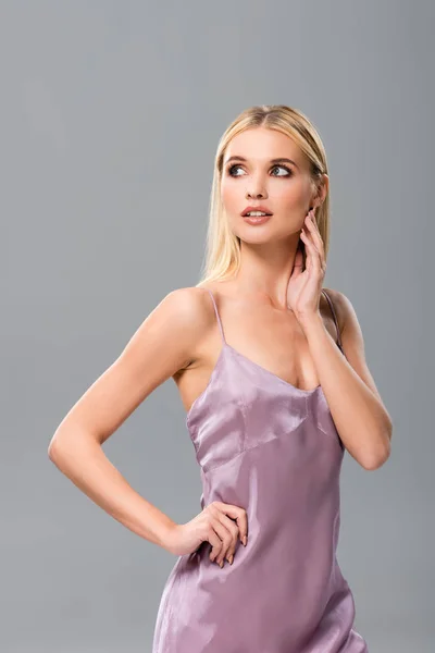 Elegant dreamy blonde girl in violet satin dress posing isolated on grey — Stock Photo