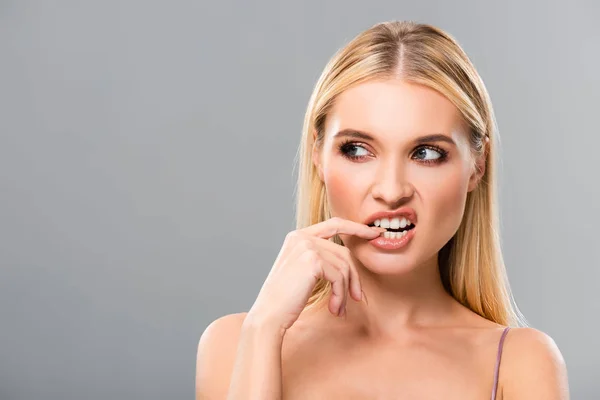 Blonde girl showing teeth and looking away isolated on grey — Stock Photo