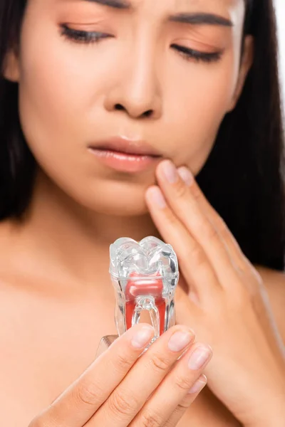 Селективный фокус грустной голой женщины с зубной болью, держащей модель зуба — стоковое фото