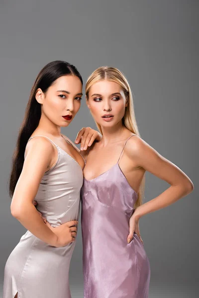 Sexy blonde and brunette women in silk dresses isolated on grey — Stock Photo