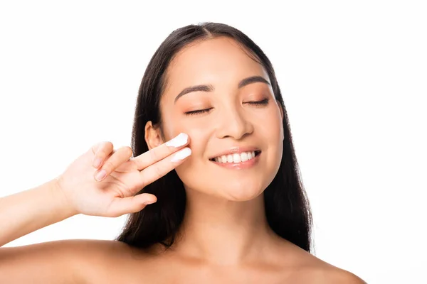 Nu belle asiatique femme avec cosmétique crème sur doigts et les yeux fermés isolé sur blanc — Photo de stock