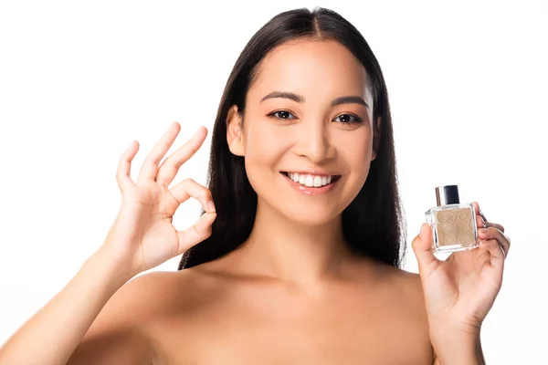 Naked beautiful asian woman holding perfume and showing ok sign isolated on white — Stock Photo