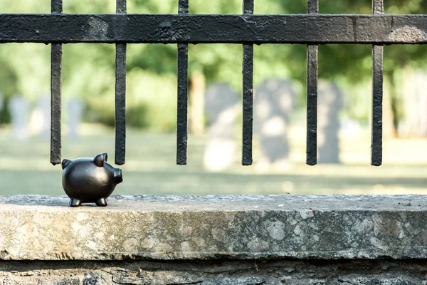 Salvadanaio nero vicino alla recinzione metallica nel cimitero — Foto stock