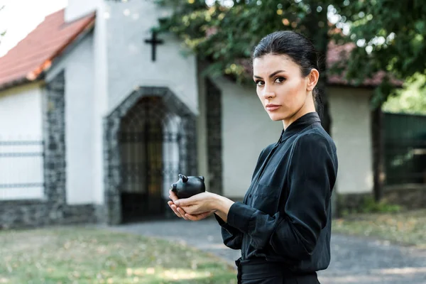 Привлекательная женщина с черной копилкой рядом с церковью — стоковое фото