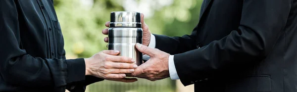 Panoramic shot of senior man and woman holding mortuary urn — Stock Photo