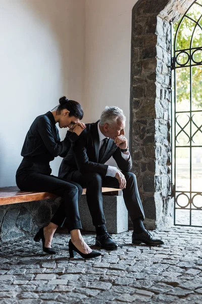Засмучена жінка і сумний чоловік сидить на лавці на похороні — стокове фото