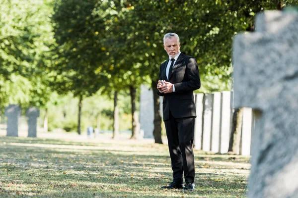 Selective focus of senior man standing on graveyard — Stock Photo