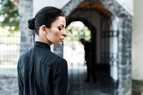 Side view of attractive woman standing near building on funeral — Stock Photo