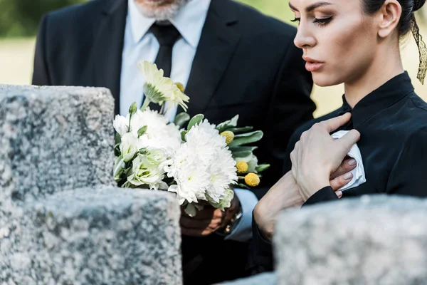 Обрезанный вид мужчины, стоящего возле гробницы, и привлекательная женщина — стоковое фото