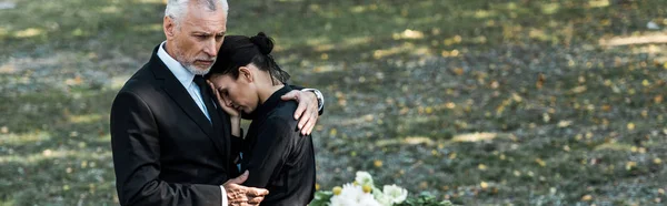Panoramic shot of bearded man hugging attractive woman on funeral — Stock Photo