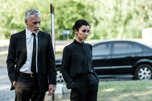 Upset man and sad woman in formal wear near car — Stock Photo