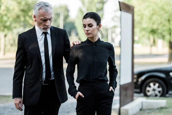 Upset senior man and sad beautiful woman in formal wear near car — Stock Photo