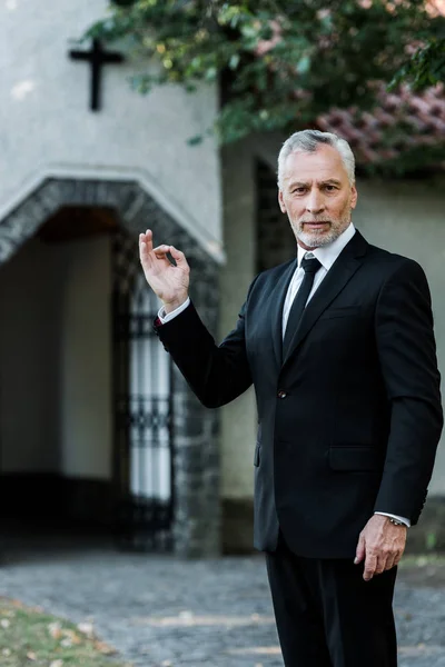 Glücklicher bärtiger Mann zeigt Ok-Zeichen in der Nähe der Kirche — Stockfoto