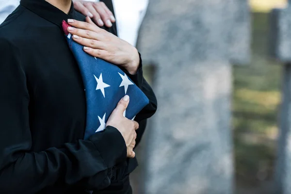 Ausgeschnittene Ansicht einer Frau mit amerikanischer Flagge auf Friedhof — Stockfoto