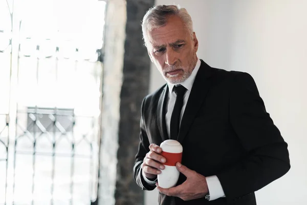 Senior man with grey hair holding mortuary urn — Stock Photo