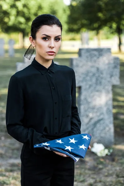 Donna attraente che tiene bandiera americana sul cimitero — Foto stock