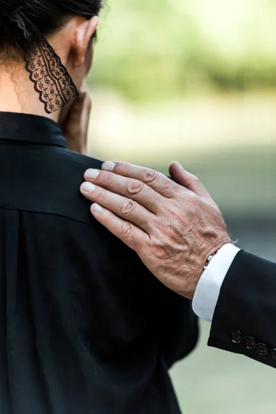 Cropped view of elderly man touching shoulder of woman on funeral — Stock Photo