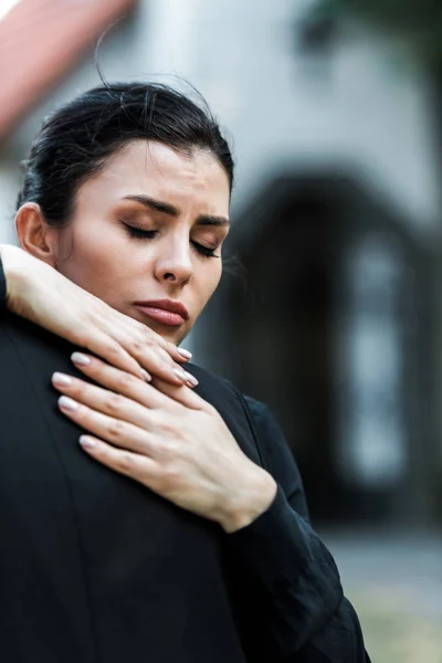 Cropped view of upset woman hugging elderly man on funeral — Stock Photo