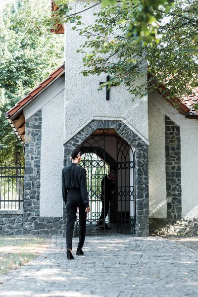 Vista trasera de la mujer caminando en la iglesia cerca de los árboles - foto de stock